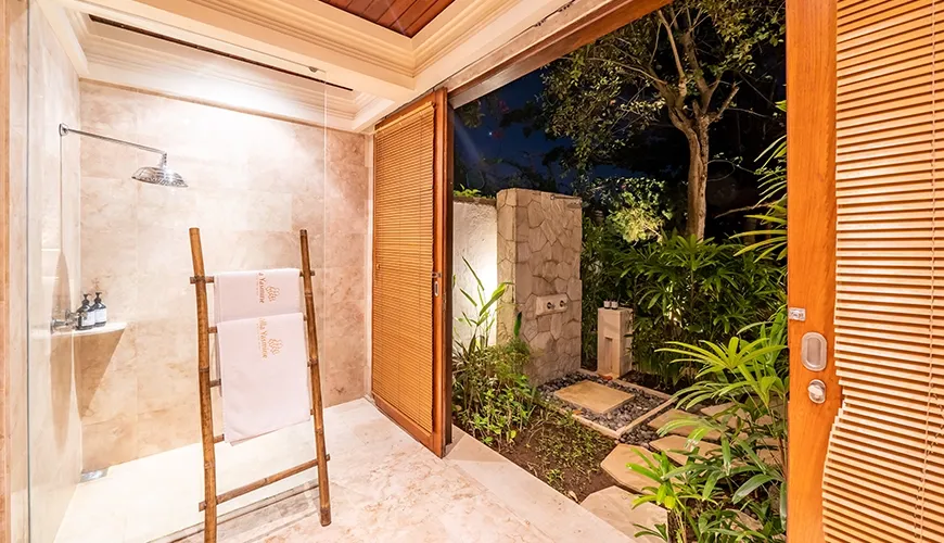 Luxurious indoor-outdoor villa bathroom featuring a glass shower and an illuminated private garden with lush tropical plants at Villa Yasmine