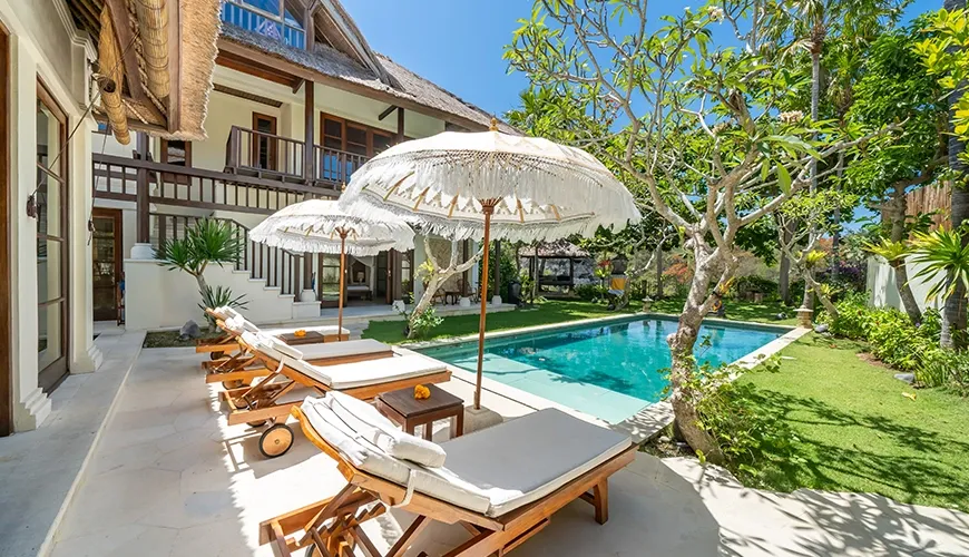 Outdoor swimming pool with sun loungers umbrellas and villa view at Villa Yasmine
