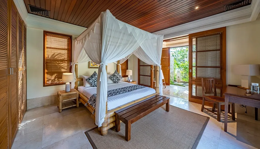 Serene villa bedroom featuring a beautiful canopy bed, rich wooden ceilings, and a private garden access at Villa Yasmine