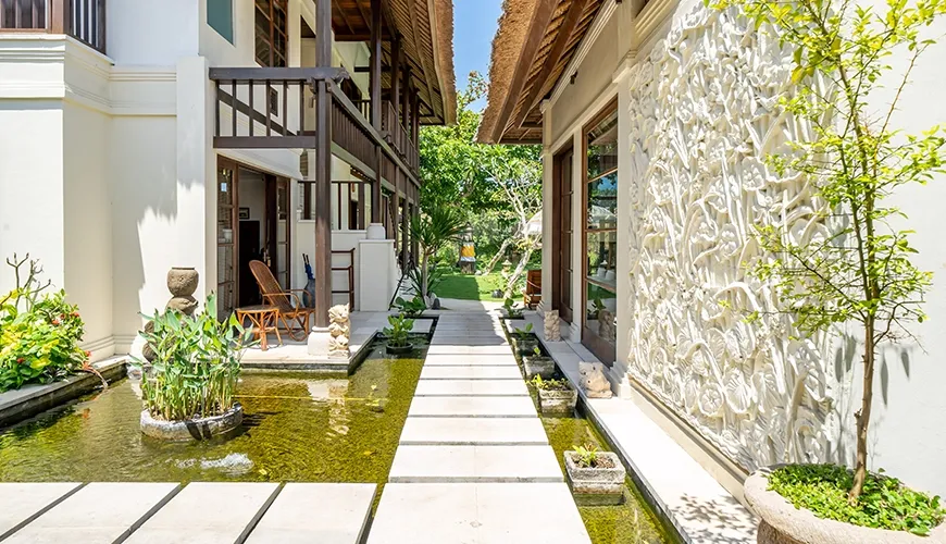 Serene villa hallway featuring stepping stones over a beautiful water feature and surrounded by lush tropical plants at Villa Yasmine