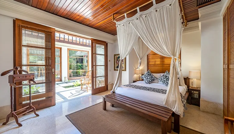 Spacious bedroom with four-poster bed and bright outdoor access at Villa Yasmine