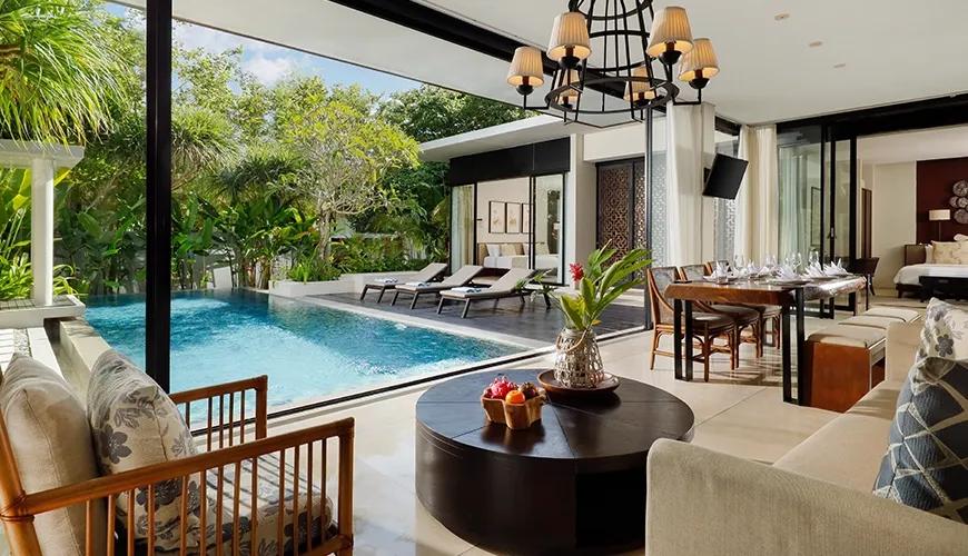 Elegant living room with a round wooden coffee table overlooking a private swimming pool at Vinila Villas Duplex