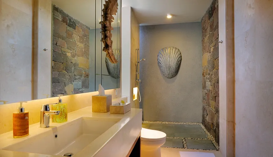 Luxury Balinese bathroom with stone walls and walk-in shower at vinila villas