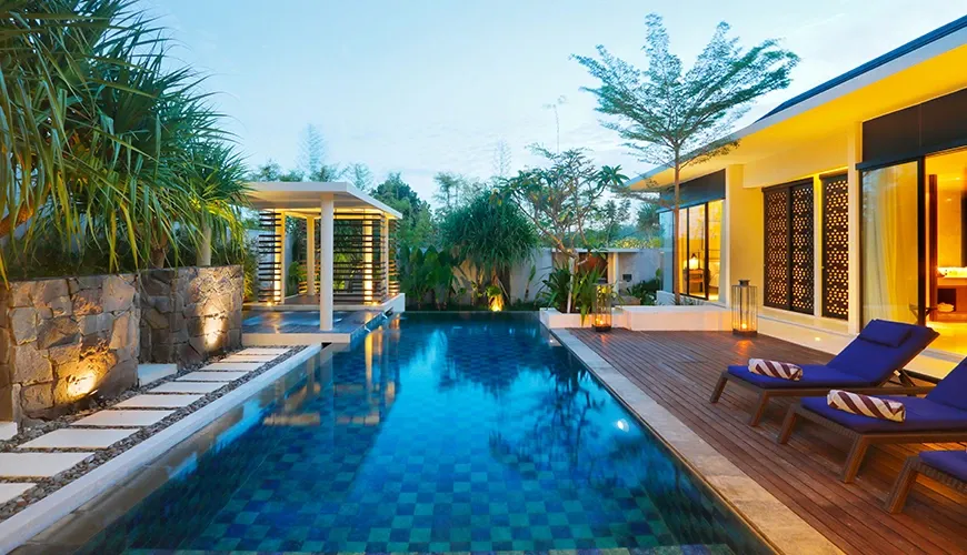 Luxury villa swimming pool with a wooden deck and lounge chairs at vinila villas